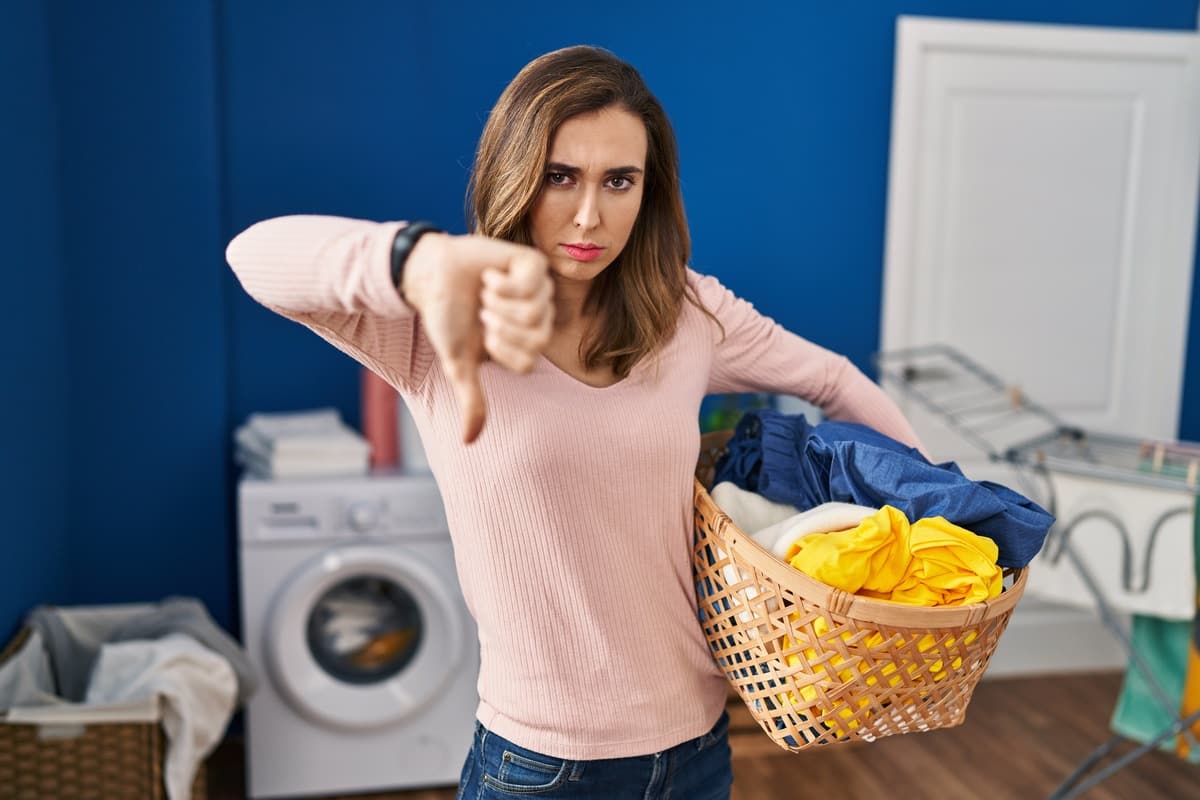 Donna con cesto del bucato in mano e un pollice abbassato
